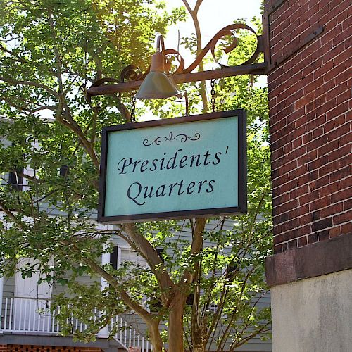 A metal sign hanging from a brick building reads 