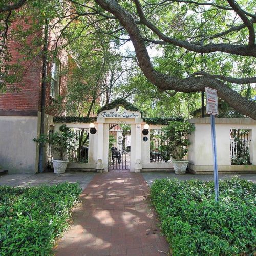 A charming entrance to an outdoor garden, with a brick pathway and a sign designating it as 